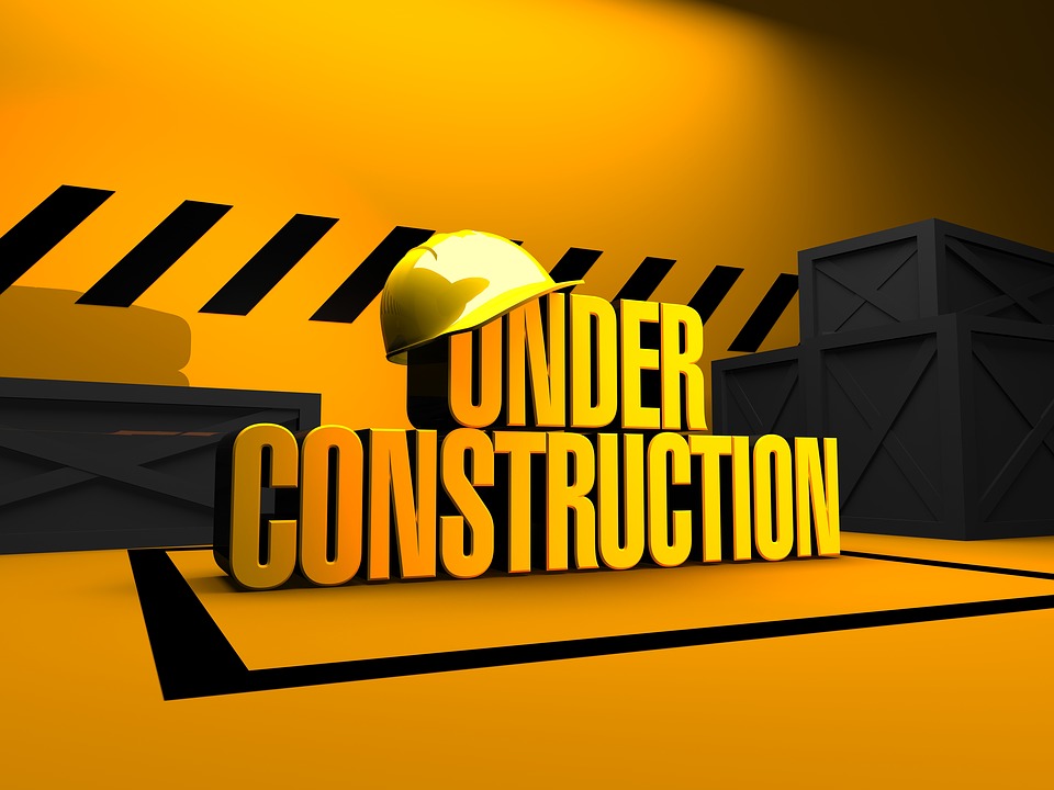 Under construction sign in yellow with a hardhat