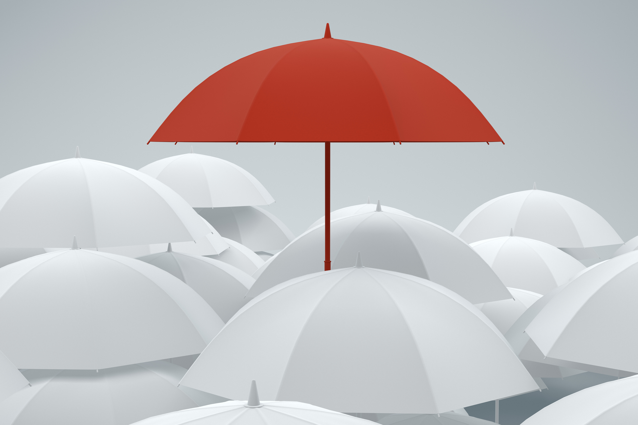 One red umbrella surrounded by white umbrellas