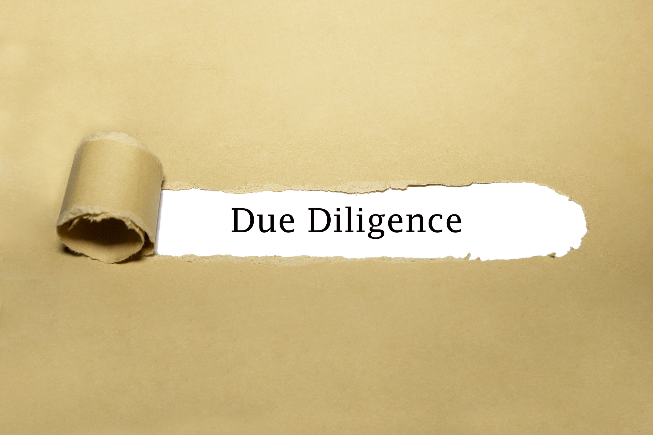 Paper torn to reveal the words 'due diligence'