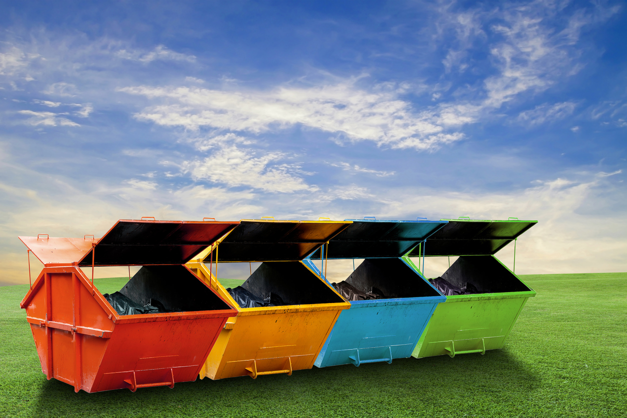 Colourful skips in a green field