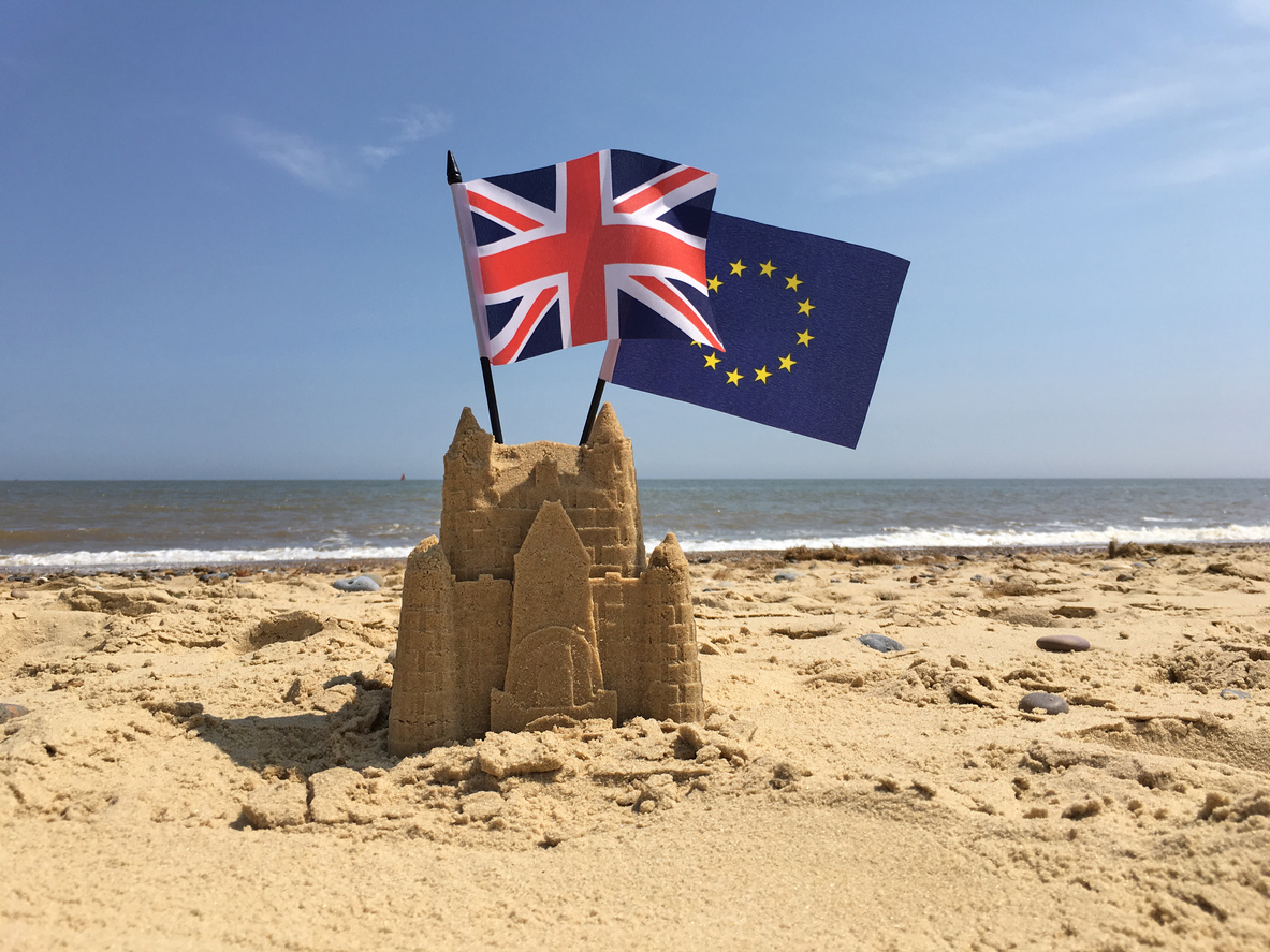 Sandcastle holding British and EU flags