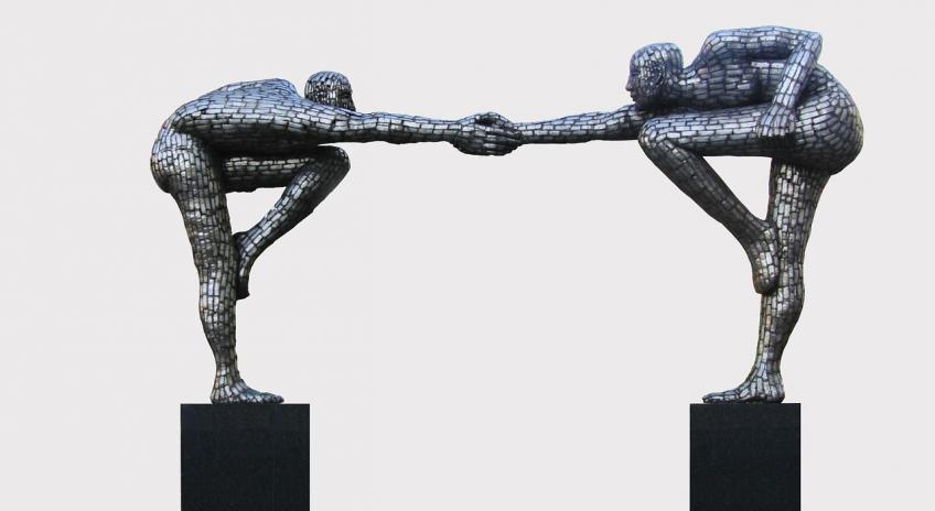 Sculpture of two people reaching out towards one another